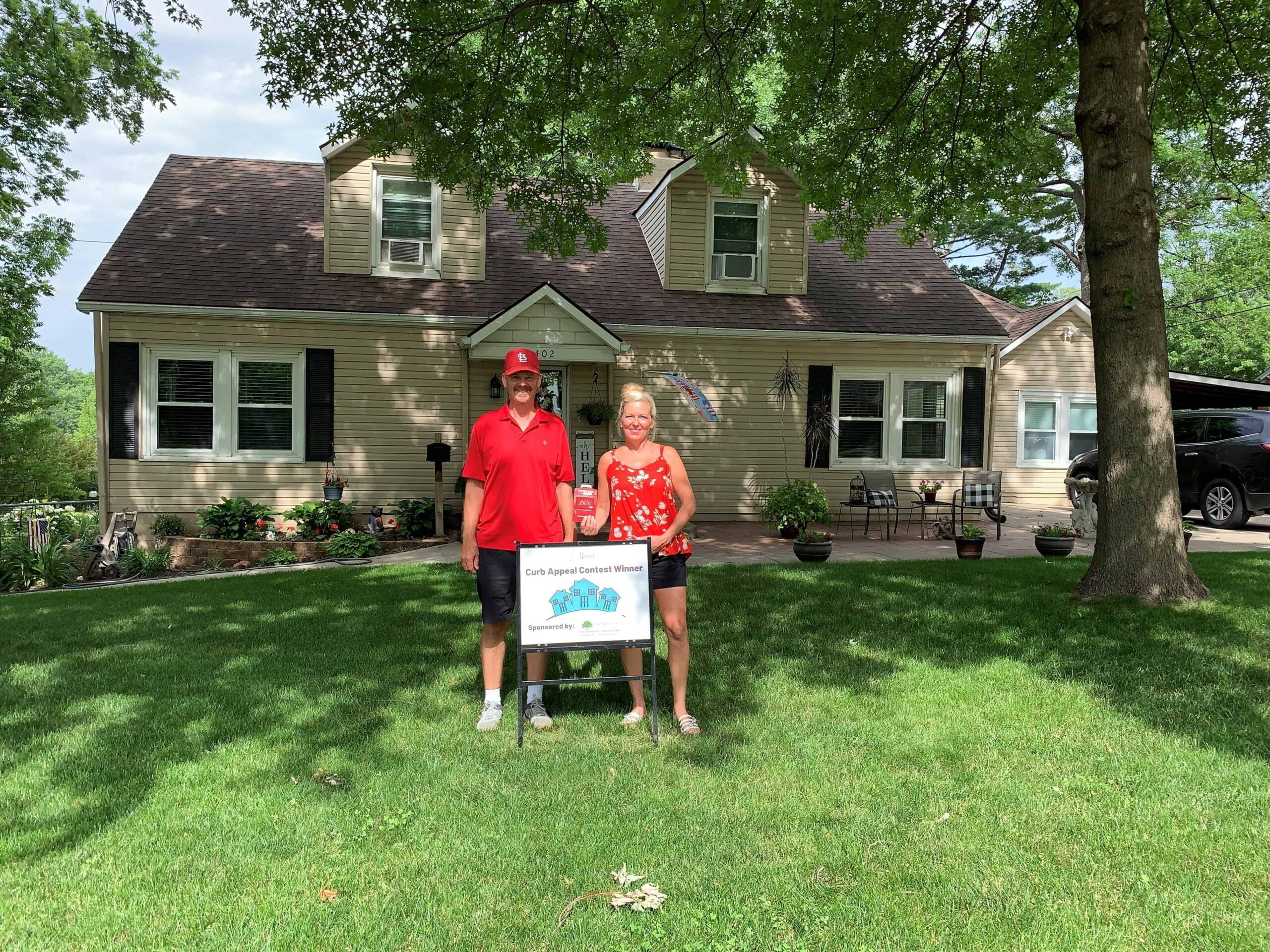 david and jill evert curb appeal winners stand in front of house with award sign
