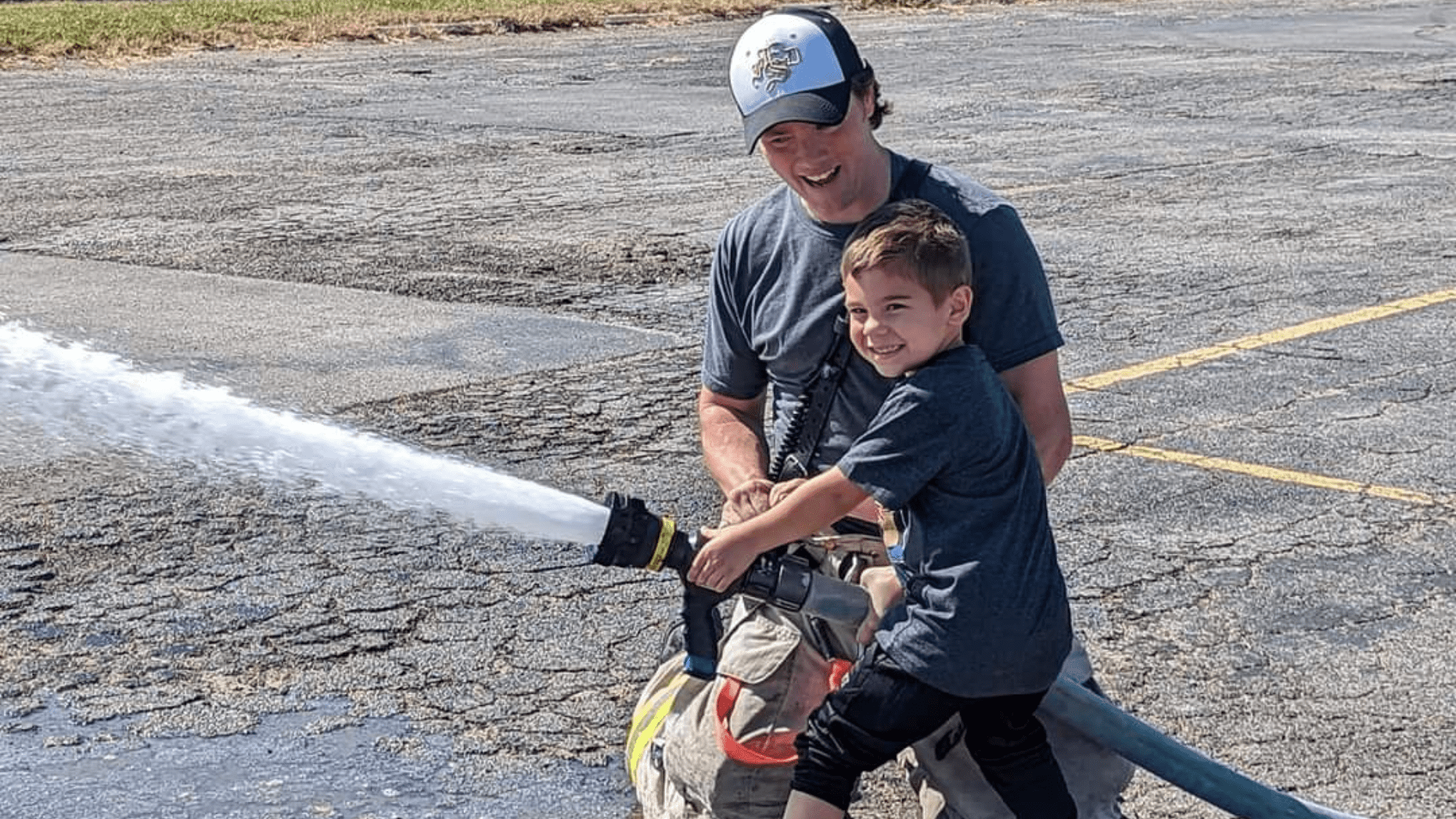 Excelsior Springs Fire Department Assistant Chief Camron White shows a Treehouse Preschool student how to use a fire hose