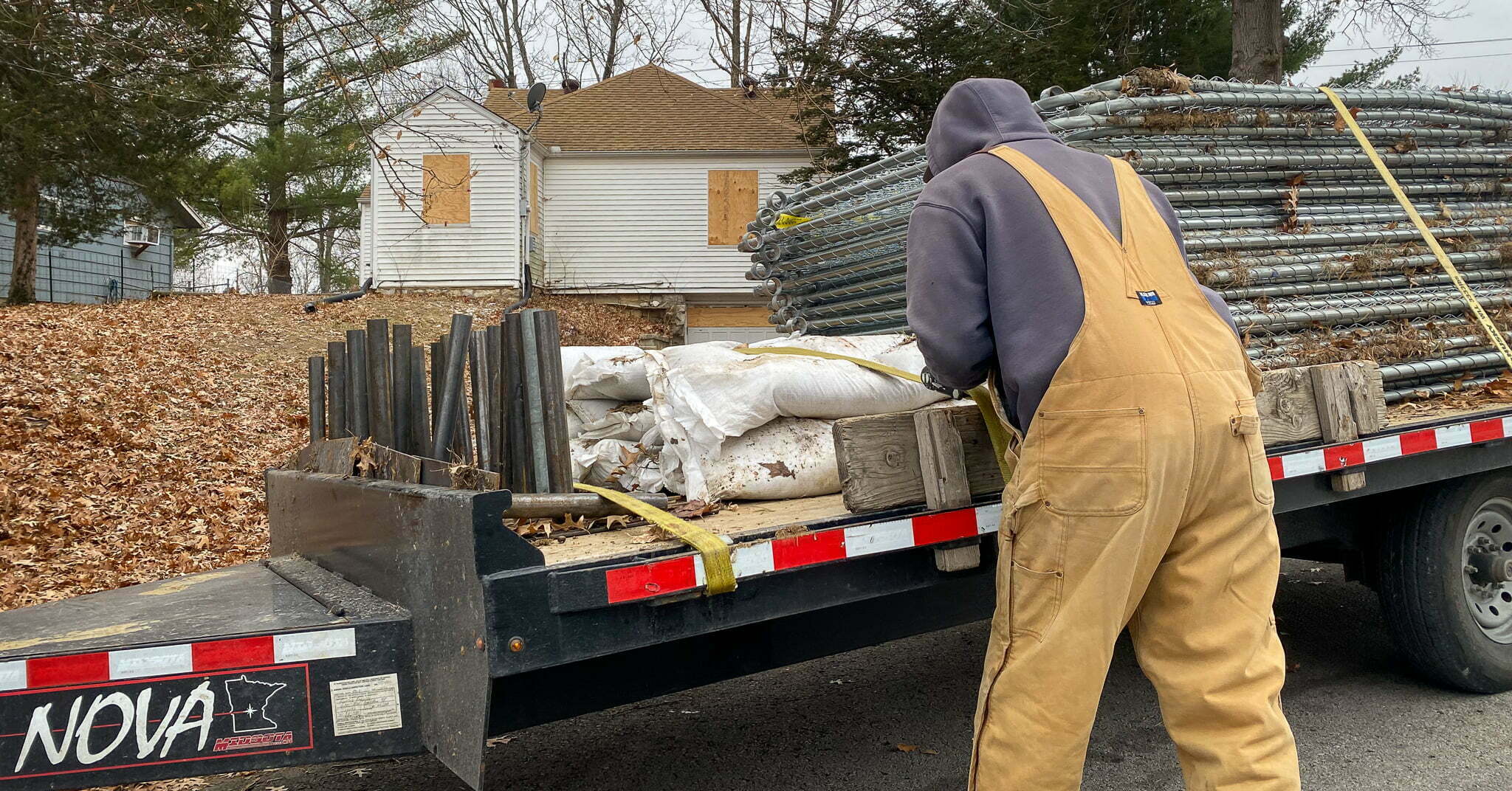 workers strap down the fence used to seal the perimeter of the alleged crime scene