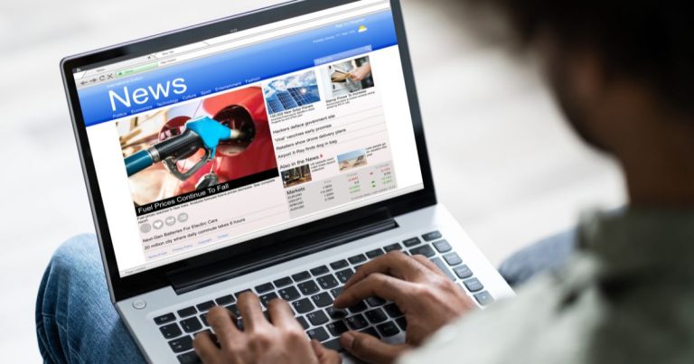 Laptop with someone typing and News on the screen