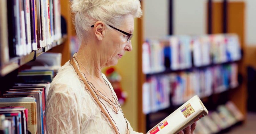 Older woman reading a book in the library