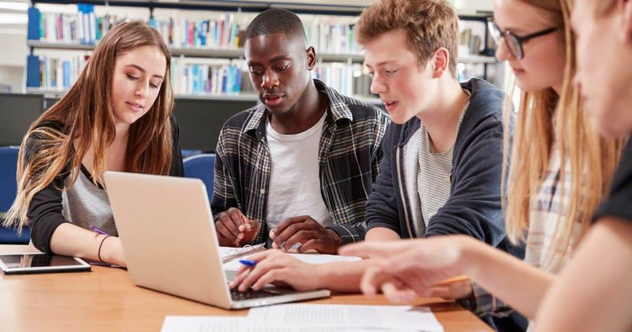 Teens around a computer in a library studying together