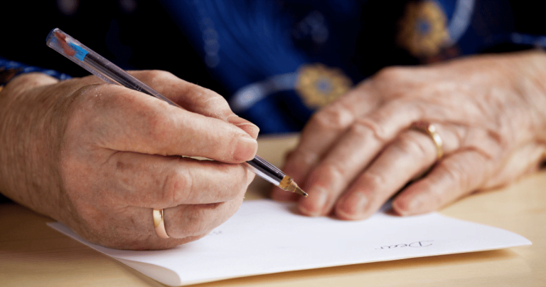 Man's hands writing a letter