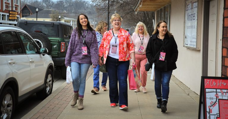 Five women walk down the sidewalk on Broadway in downtown Excelsior Springs during the Chocolate Tour