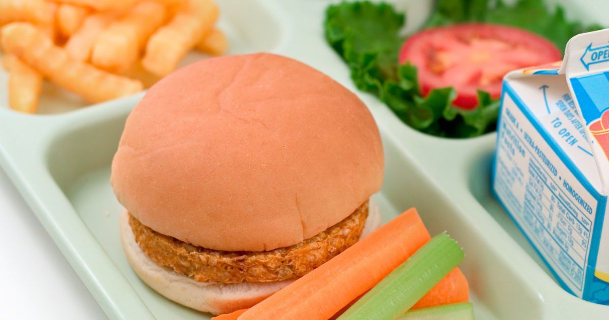 school lunch tray with a chicken sandwich, fries, and vegetables