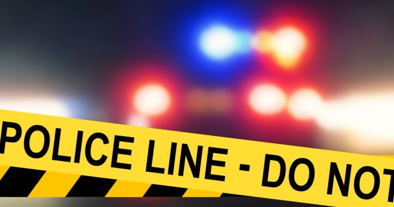 yellow police line do not cross with police car lights blurred in the background