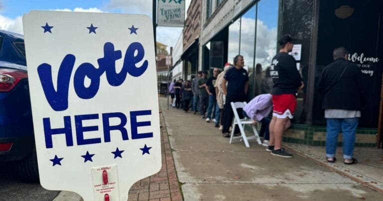 Vote here sign with voters in line at the Montgomery Event Venue in Excelsior Springs