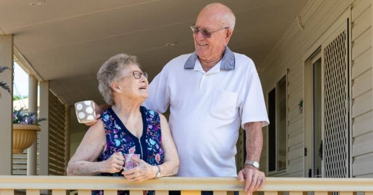 One male and one female senior citizens standing together on a porch
