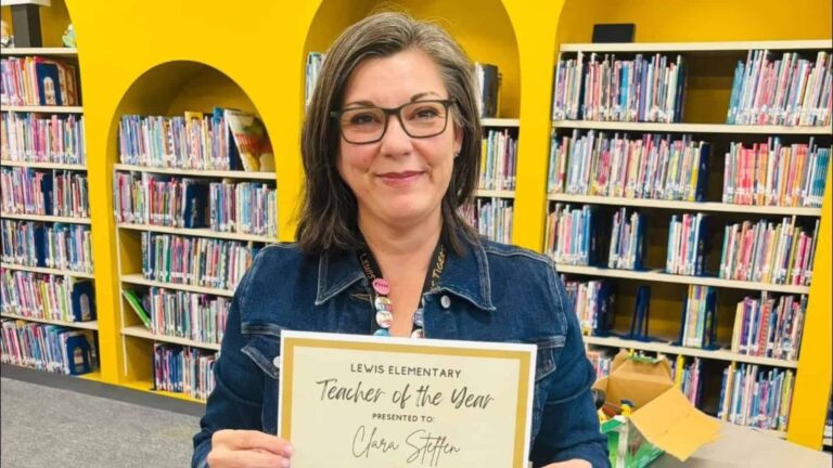 Clara Steffen standing proudly while holding her Teacher of the Year award.